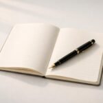 Minimalist white desk with notebook and fountain pen representing thoughtful reference and educational writing